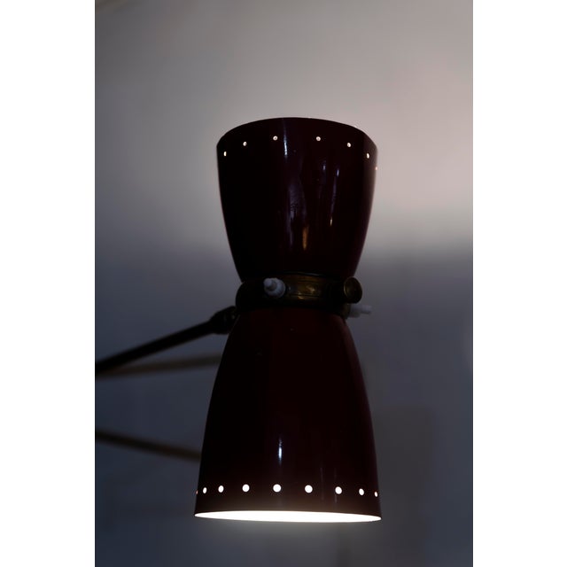 French adjustable wall lamp from the 1950s, attributed to Robert Mathieu (1921–2002). Made of red lacquered metal and...