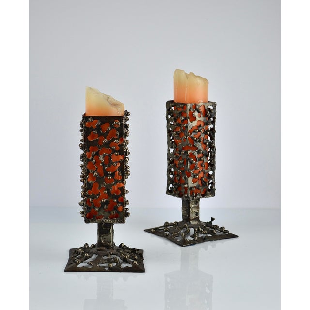 Striking pair of handmade Brutalist iron candleholders, circa 1970. Each candleholder features a tall rectangular openwork...