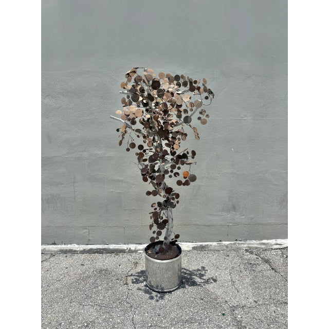 Whimsical sculptural tree featuring cascading clusters of hand-formed metal disc leaves in varied patinated tones, mounted...