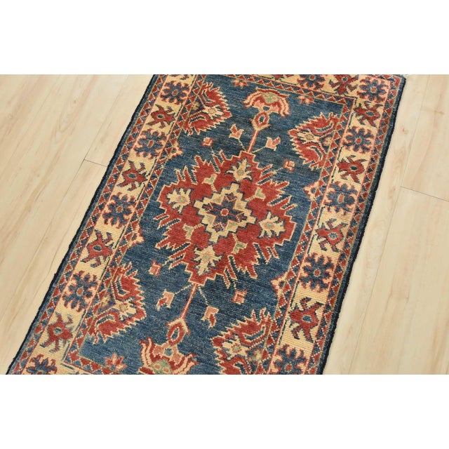 A tribal Caucasian Kazak rug hand-knotted with an all-wool pile on a cotton foundation. This oriental rug features a...
