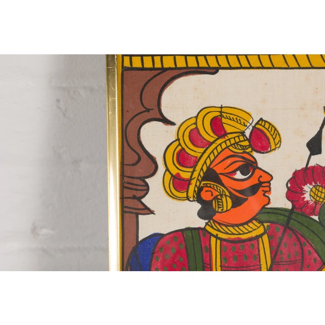 An antique Indian hand-painted folk art painting depicting musicians and archers in a brass custom frame. Step into a...