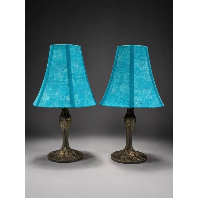 Matching pair of decorative table lamps featuring vibrant turquoise textured fabric shades and dark bronze-tone sculptural...