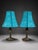 Matching pair of decorative table lamps featuring vibrant turquoise textured fabric shades and dark bronze-tone sculptural...