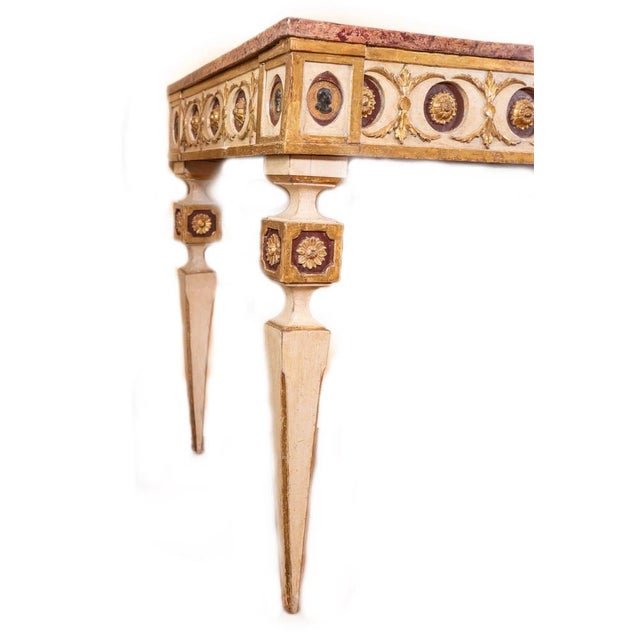 Elegant Tuscan console lacquered and gilded in gold leaf, with narrowed pyramidal feet. The border consists of golden...