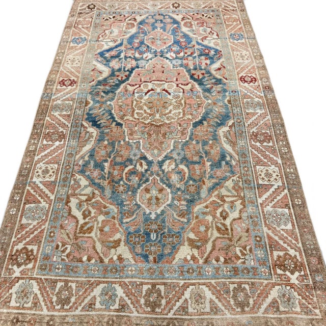 An intriguing antique rug with a distinctive elongated pink medallion set against a blue field. The composition is...