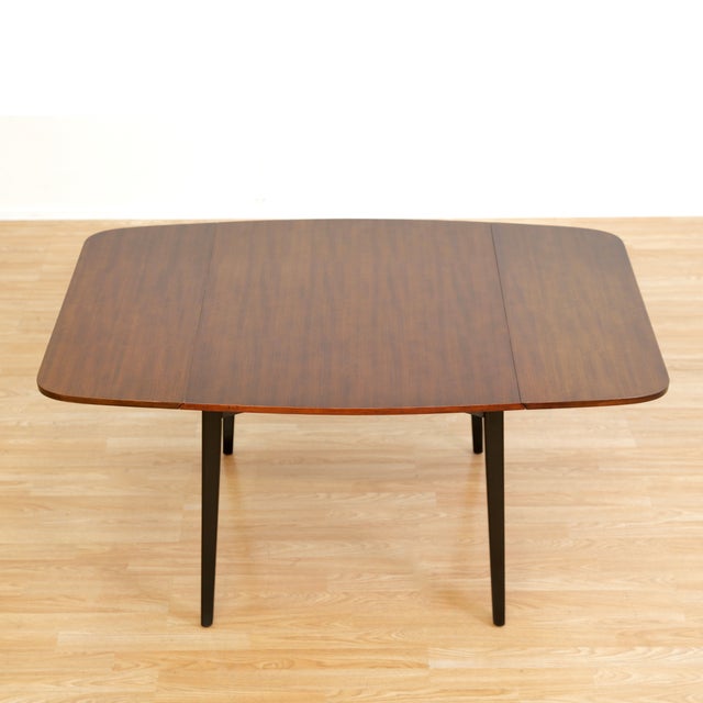 This mid-century drop leaf dining table was produced by in England by E Gomme (G Plan) during the 1950s. With a stunning...