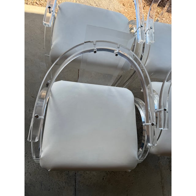 This is a set of four vintage Charles Hollis Jones-style Lucite armchairs with a white upholstered seat and casters. The...