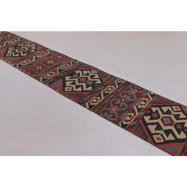 Made with handwoven wool circa 1950-1960, this 2x15 vintage flat-weave runner Kilim is a particularly impressive and...