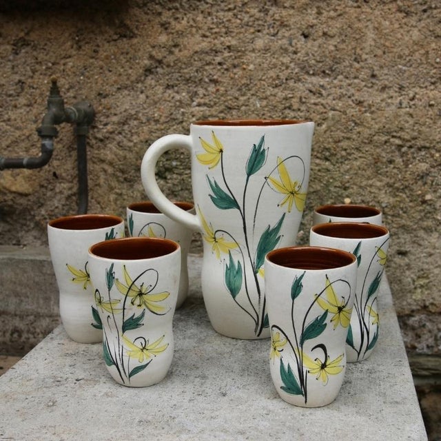 A mid-20th-century french handcrafted ceramic coffee or orangeade set, made in the style of vallauris pottery. Against a...