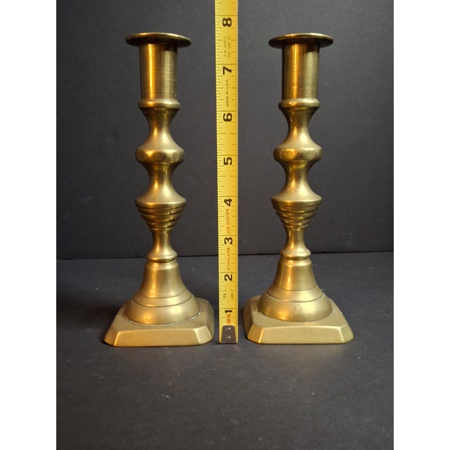 A fine pair of antique English brass candlesticks featuring multi-knop stems and square stepped bases with clipped...