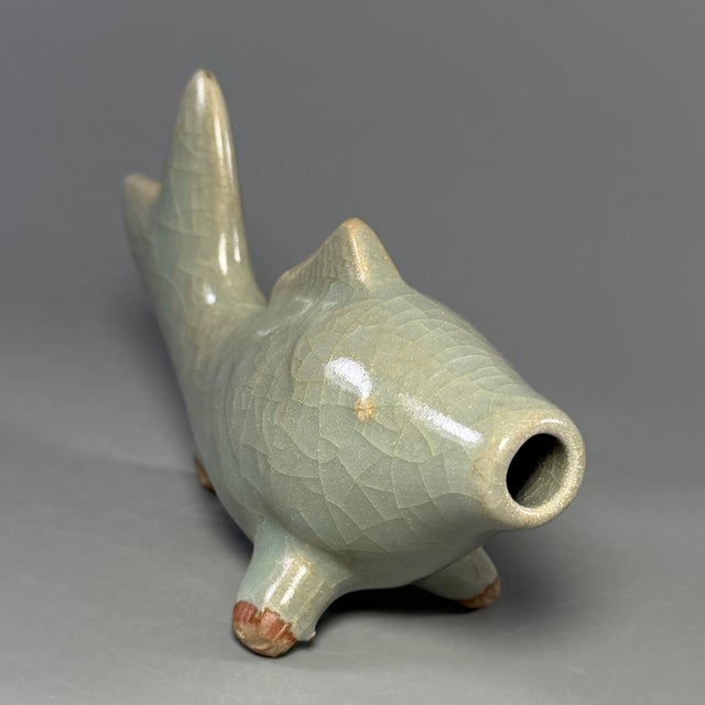 This antique Chinese Longquan celadon water dropper is crafted in the form of a fish. It is covered in soft celadon glaze...