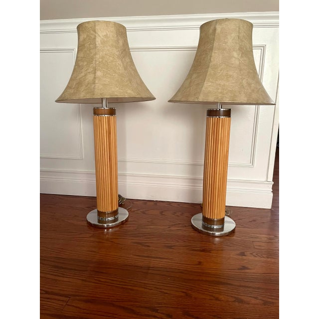 Mid century pencil reed table lamps. Chrome base and wood accents. Vinyl shades similar to a faux goatskin design. The...