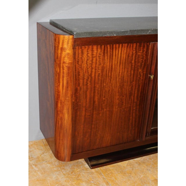 Art Deco period sideboard in solid mahogany, it opens with three sliding doors, one of which is glazed, black marble top,...