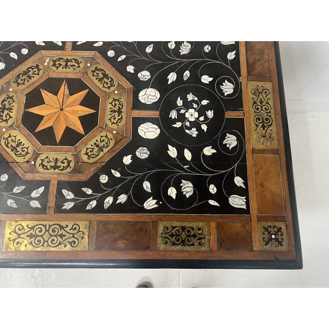 Table with trapezoidal base in blackened wood The top has a wood and engraved brass frame Decorated on a black background...