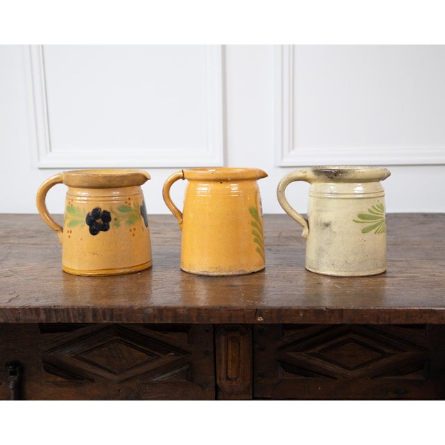 Charming 19th-century French terracotta pottery pitchers, each displaying the warm, rustic character of traditional...