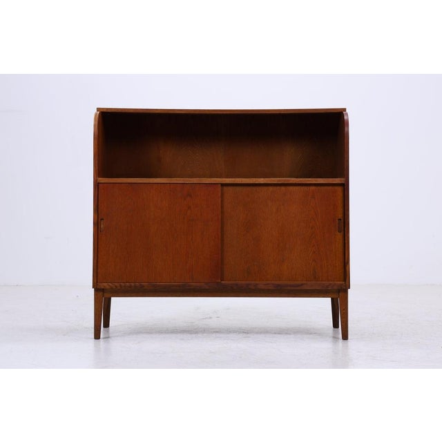 Vintage chest of drawers with beautiful teak grain and distinctive rounded sides. Behind the sliding doors are several...
