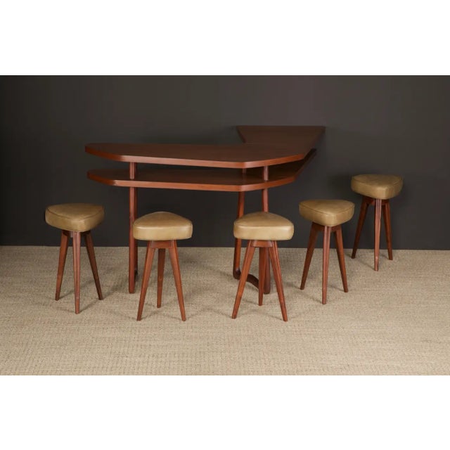 This sculptural boomerang bar with five leather barstools were sculpted from hefty walnut in circa 1950s, attributed to...