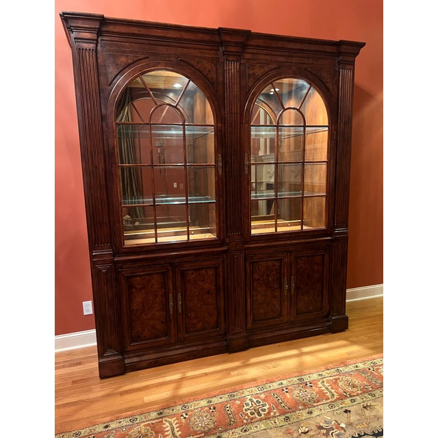 Timeless two-piece illuminated display cabinet by Henredon. This piece features arched doors, removable thick glass...