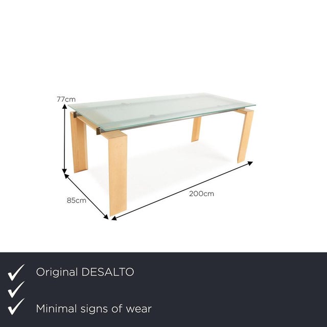 The Stilt dining table from DESALTO consists of a glass top and stands on a wooden frame. It is characterized by its...