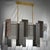 Murano chandelier with an elongated design with a brass structure and single glass in bronze, transparent and silver....