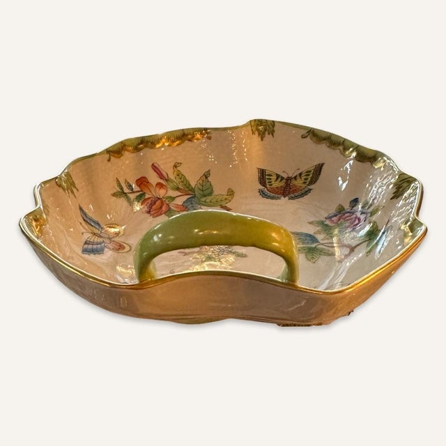 Late 20th century Herend leaf dish with hand-painted flower and butterfly decoration. Green stem handle on one side of the...