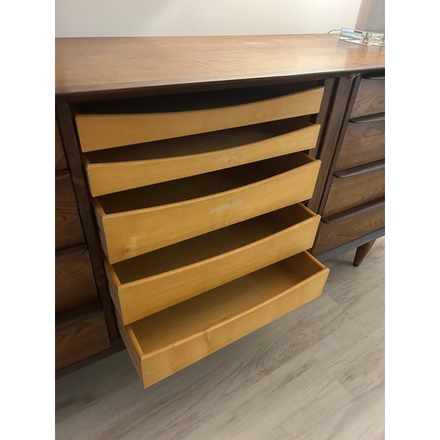 A stunning example of mid-century modern design, this long walnut dresser offers both functionality and sculptural beauty....