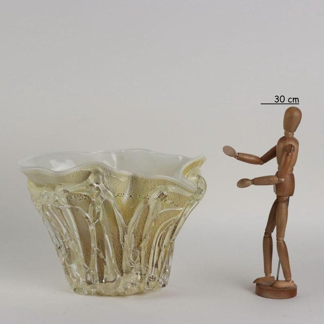 Irregularly shaped glass vase in shades of yellow with gold and silver leaf inclusions. The body of the vase features...