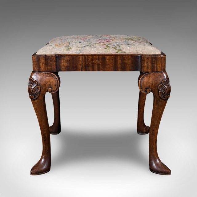 This is an antique Queen Anne revival dressing stool. An English, mahogany and needlepoint footstool, dating to the high...