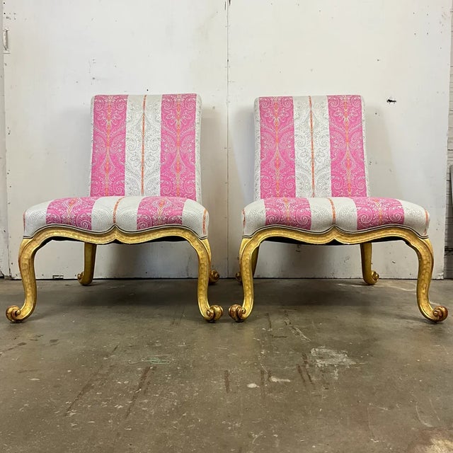 A striking pair of Kent-form accent chairs featuring carved giltwood frames with graceful serpentine aprons and scrolling...