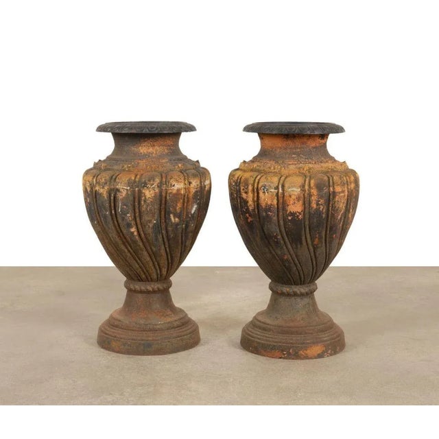 Pair of large rustic cast iron garden urns made in Italy in the 1900's; each adorned with gadroon motifs all around as...