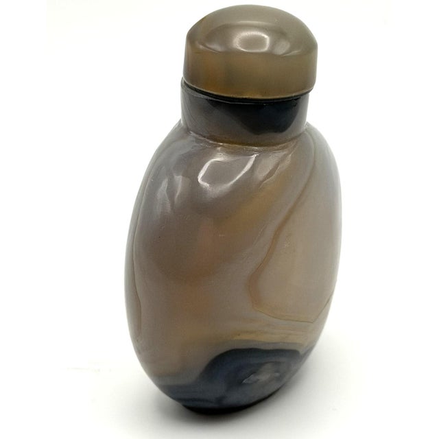 The well hollowed snuff bottle is made of agate with diagonal and horizontal bands giving the bottle an interesting and...