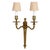 A pair of Neoclassical gilt wall sconces, each featuring two gracefully scrolled arms and candle-style sockets with a...