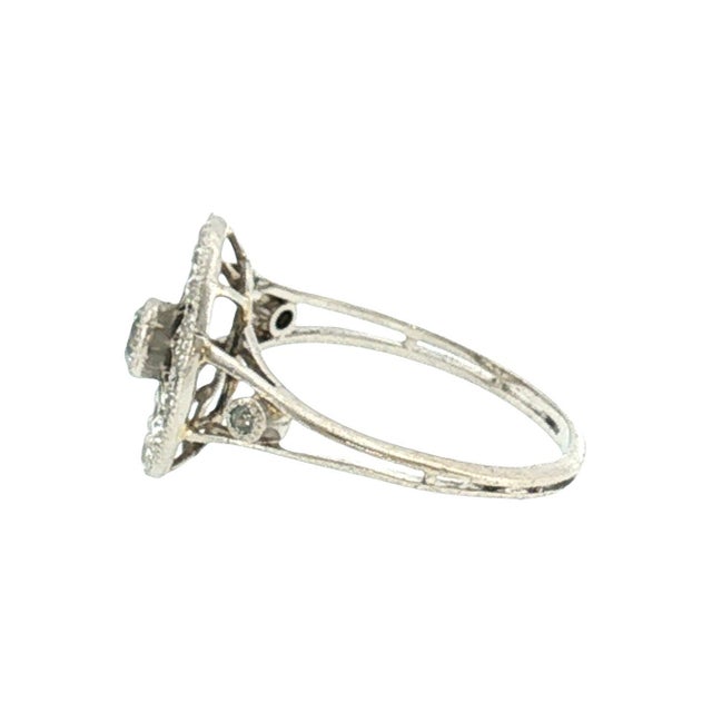 An Edwardian platinum hand-fabricated cocktail ring featuring 21 old mine-cut diamonds weighing approximately .35 carats....