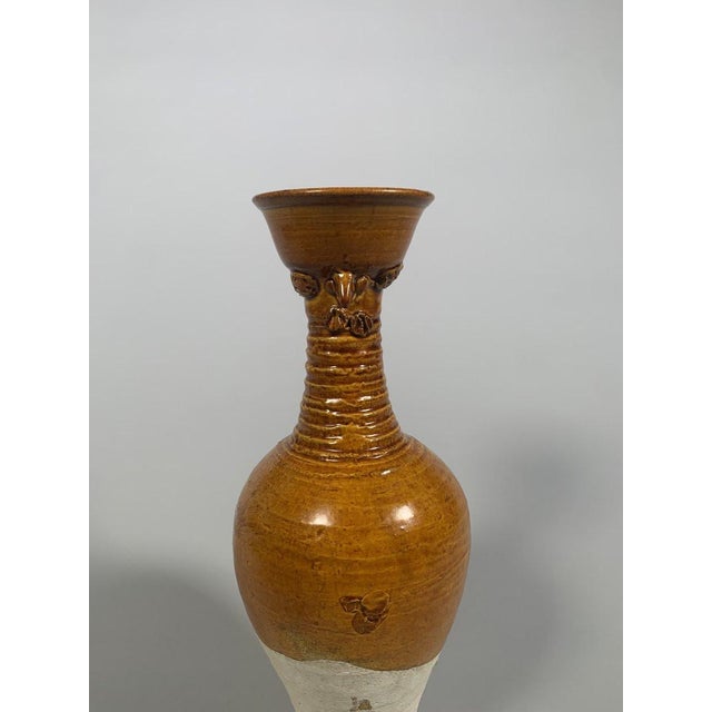 A covered terracotta vase with an amber glaze, Tang Dynasty (618-907). The upper part, covered with an amber glaze, has a...