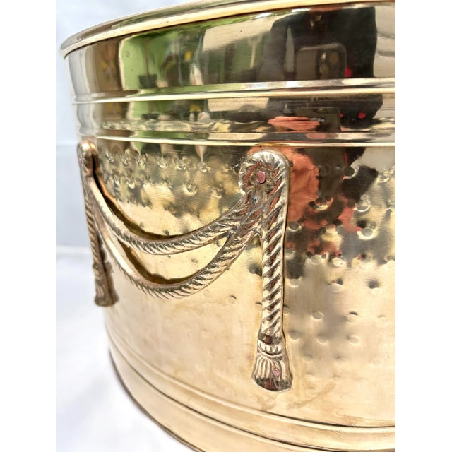 A handsome 1980s hammered brass magazine holder featuring elegant swag rope and tassel detailing. This Hollywood Regency...
