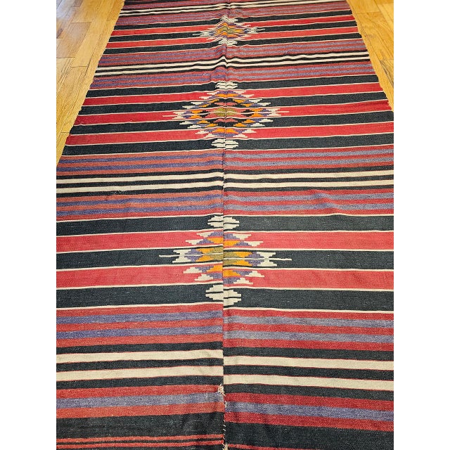 This vintage handwoven kilim rug is a flat-woven with a color palette inspired by the natural beauty of the American...