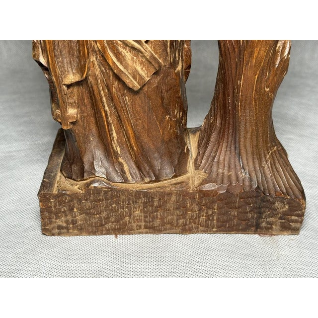 Hand-carved wooden religious figure accompanied by a decorative candle holder.