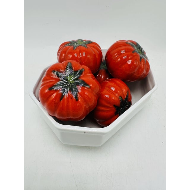 This is a decorative ceramic dish containing a set of realistic ceramic tomatoes, likely used as a centerpiece or kitchen...