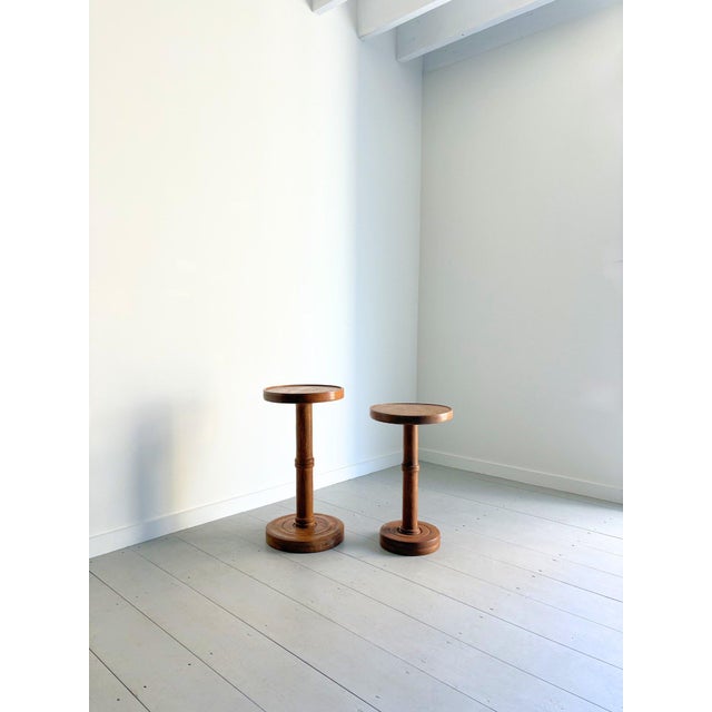 A handsome pair of hand turned wooden side tables in complementary sizes. This set of 20th Century occasional tables has...