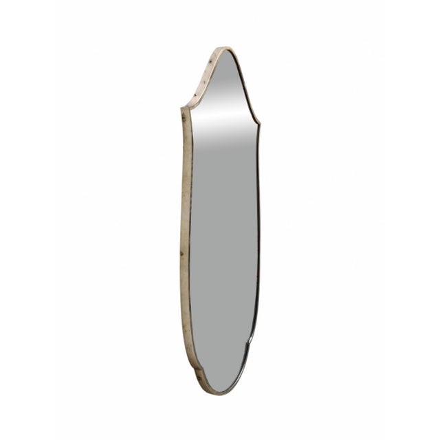 A shield-shaped brass mirror, designed in the style of the renowned designer Gio Ponti. The mirror features a...