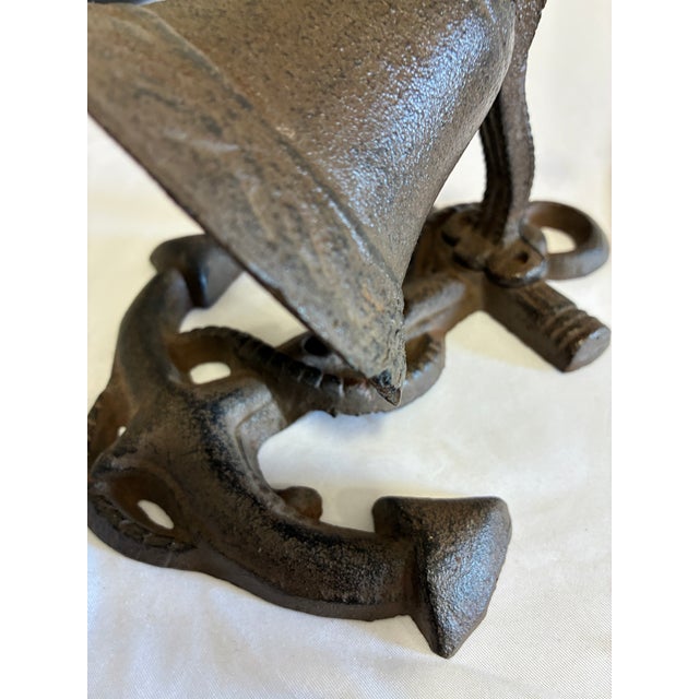 A weighty cast iron bell mounted on an anchor-form base, detailed with cast rope trim along the shank and arms and...