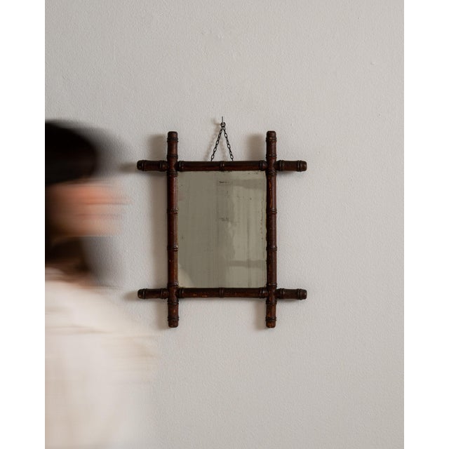 Here is a mirror, its natural faux-bamboo frame, hanging chain the first thing to catch the eye. It was made in France...