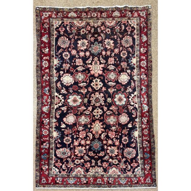 Antique hand-knotted rug from the Hamedan region of western Iran, featuring a dense allover floral design on a deep navy...