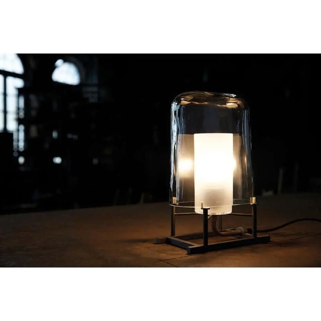 Table lamp of clear mouth blown Murano glass, anthracite painted iron and natural brass designed in 1984 by Carlo Moretti...