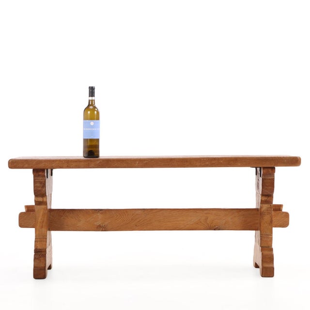 A striking large-scale coffee table featuring a solid oak trestle base with boldly gouged and carved supports joined by a...