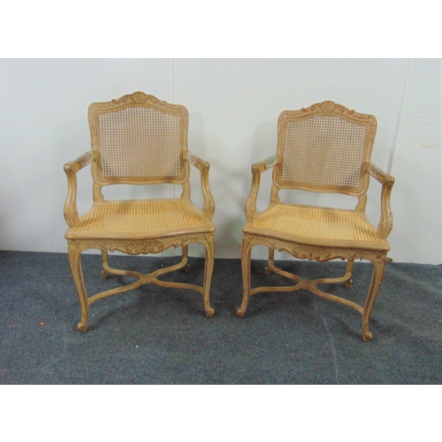 A pair of Louis XV style arm chairs, faux painted frames with carved accents, caned seats and backs, upholstered pad arms,...