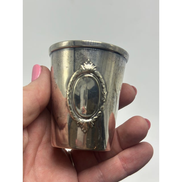 This appears to be a vintage alpaca silver beaker or tumbler, featuring a clean tapered form accented by an applied...