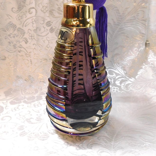 This is a triangular purple art glass perfume bottle with a sticker on one side that only reads JL. The bottle has three...