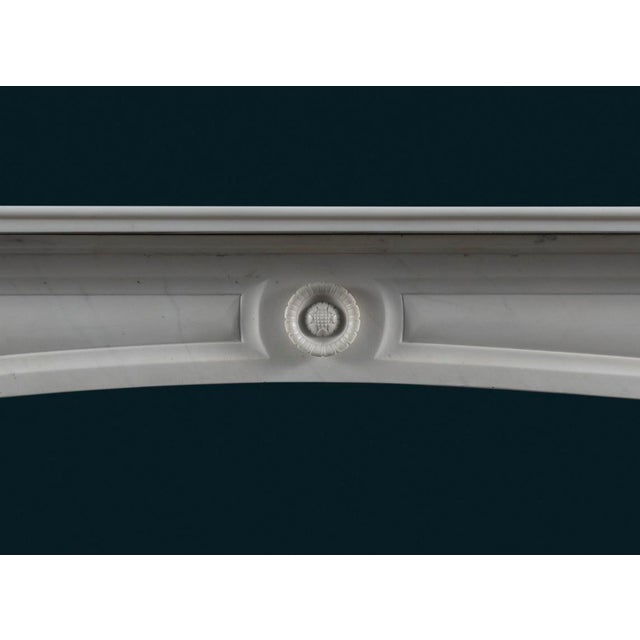 A late Regency period Carrara marble fireplace surround, the stepped shelf above panelled frieze with elegant shallow arch...