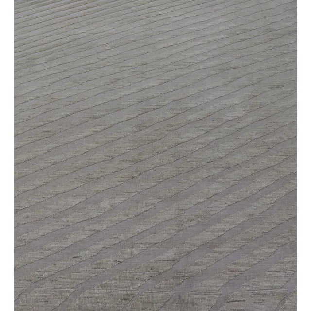 Measures: 9'4 x 11'9. This modern casual tribal rug has been hand-knotted in wool. The rug features a modern sub-geometric...